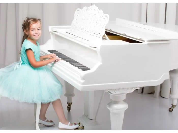 白いピアノを弾くドレスの女の子