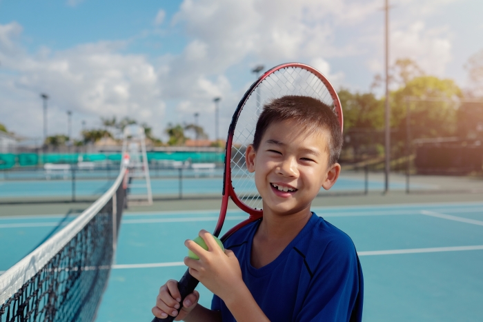 笑顔でテニスラケットを持つ男の子