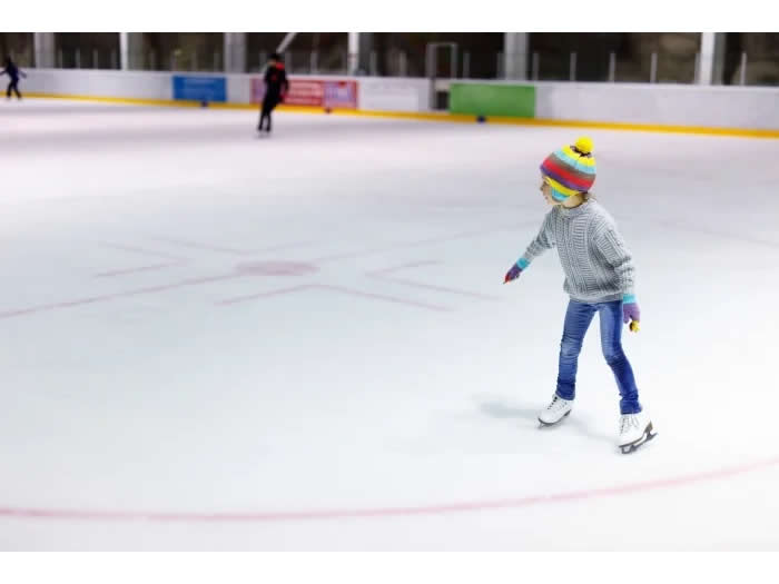 カラフルな帽子をかぶってスケートの練習をするこども