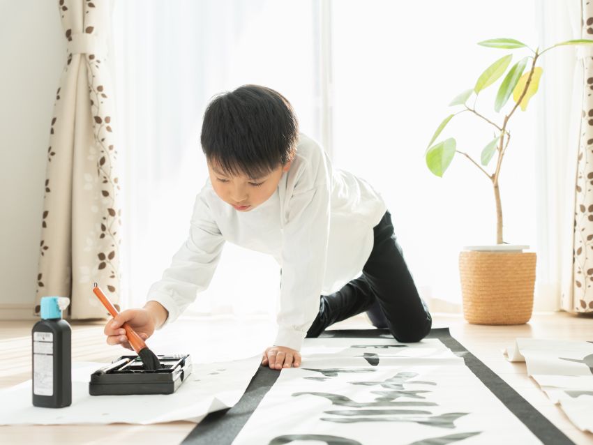 墨汁で書き初めをする子供