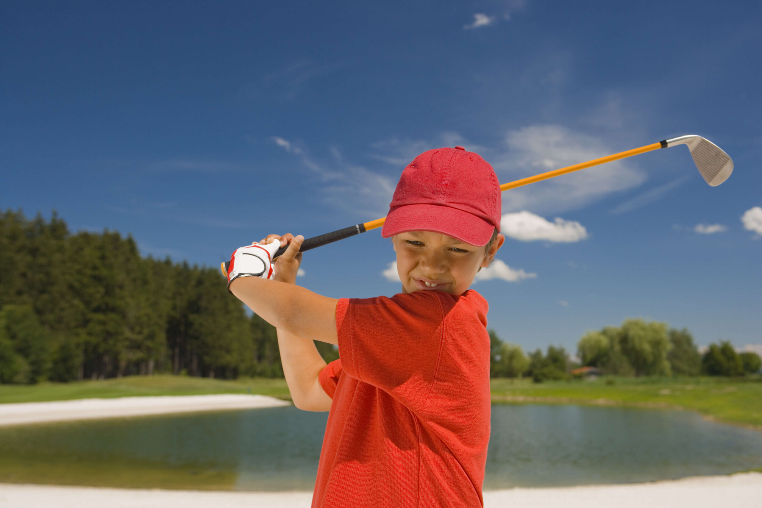 赤い帽子を被ってゴルフをする子ども
