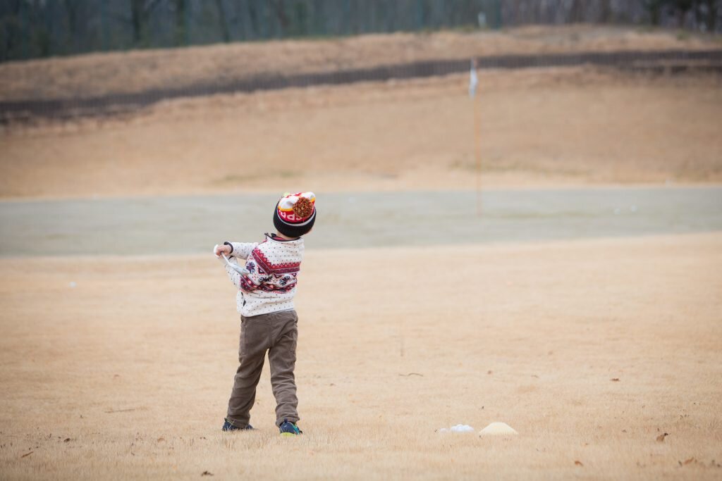 冬のゴルフ場でゴルフをやる子供