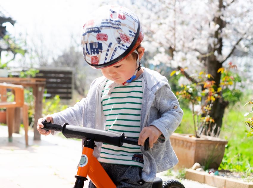 ヘルメットを付けてキックバイクに乗る子ども
