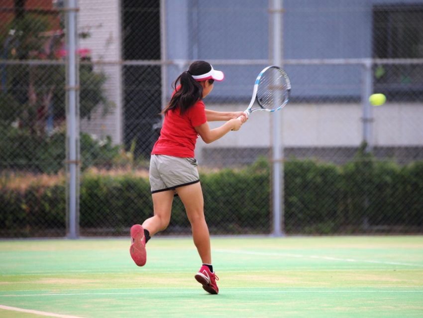 テニスでバックハンドを打つ女の子
