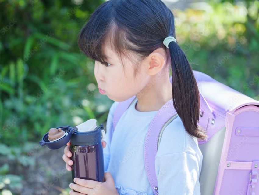 水筒で水分補給をする小学生の女の子