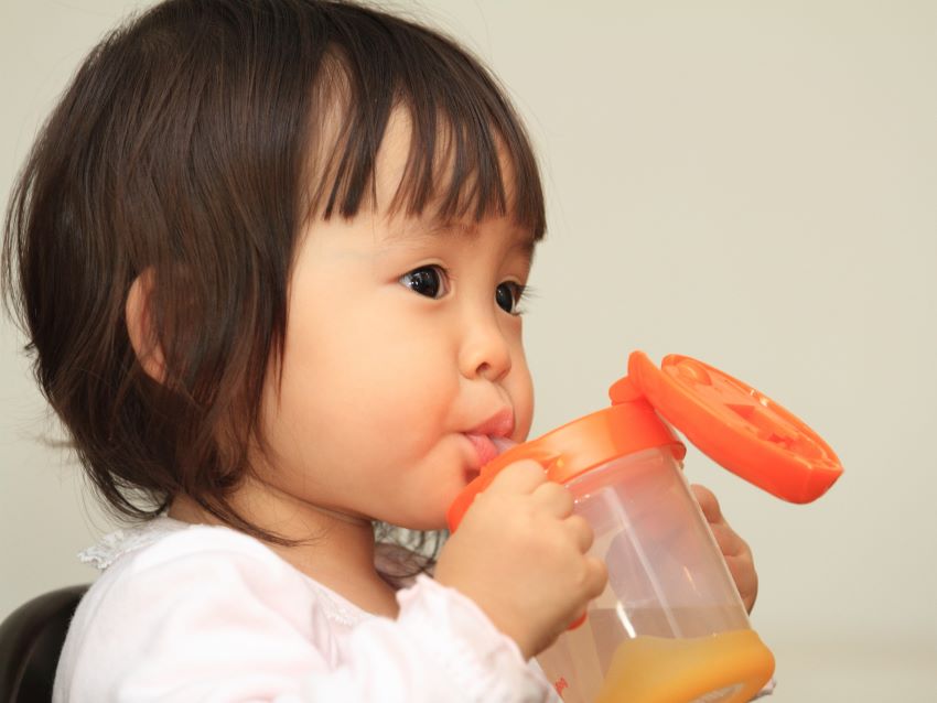 ベビーマグで飲み物を飲む子供