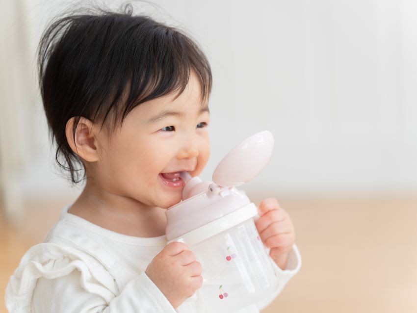 ベビーマグで飲み物を飲む女の子