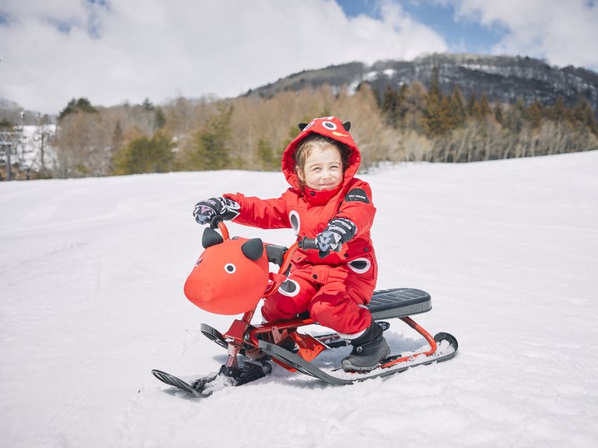 「赤べこウェア」を着て「赤べこそり」に乗る子供